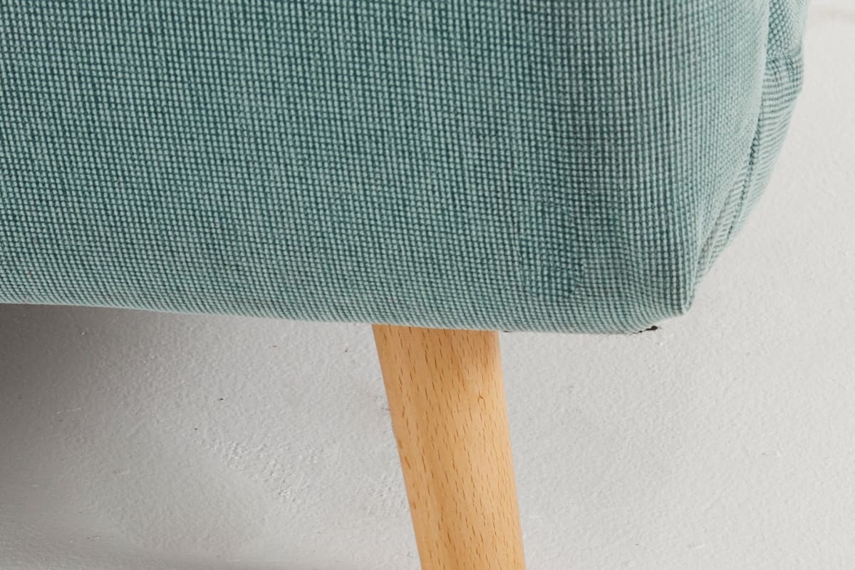 Dettaglio del tessuto e delle gambe in legno della poltrona letto NIO