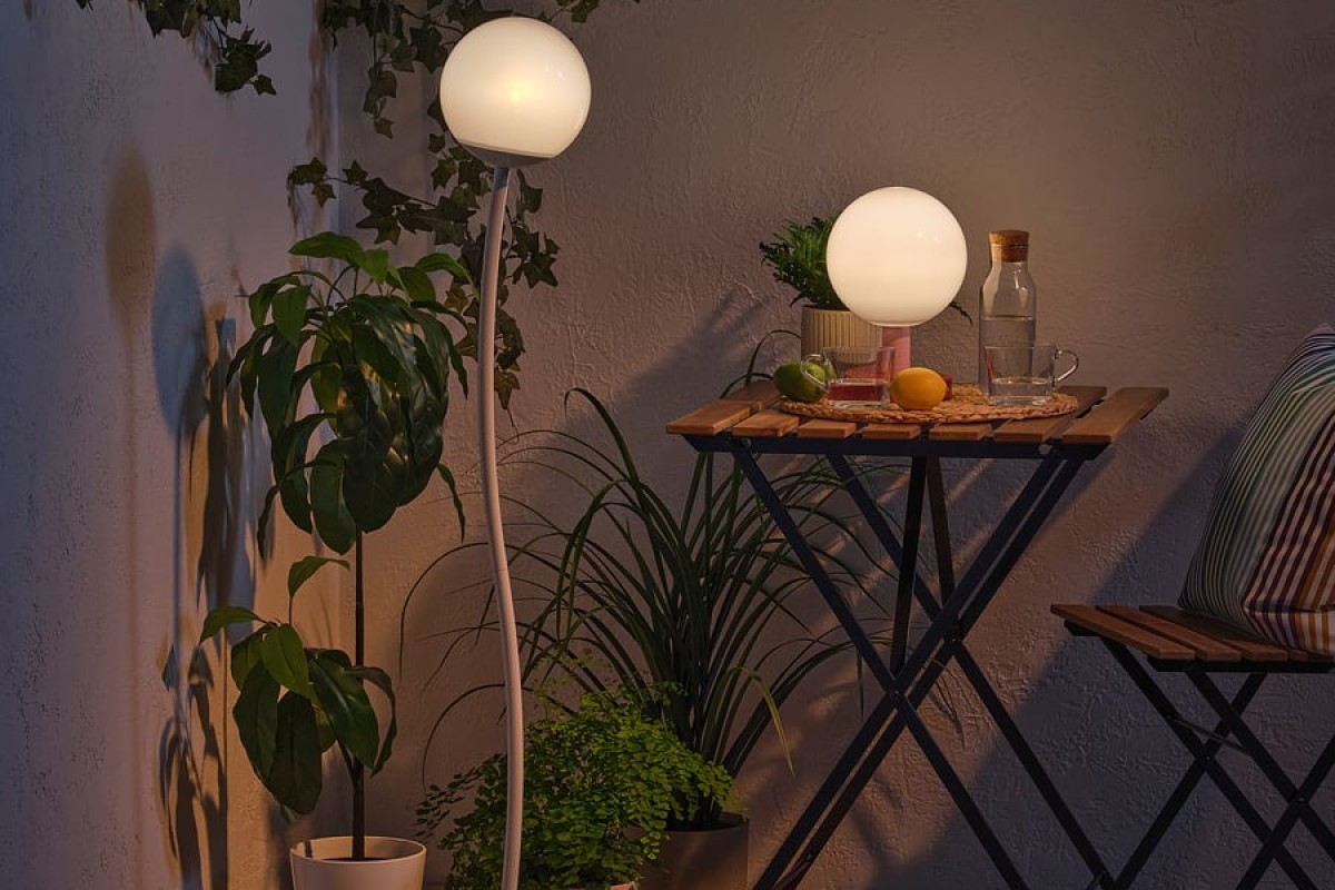 Lampada solare IKEA SOLVINDEN su balcone estivo con tavolino e piante