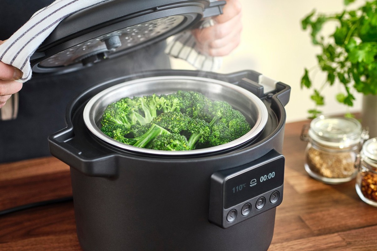 Persona che usa il multicooker IKEA TILLREDA per cuocere verdure al vapore
