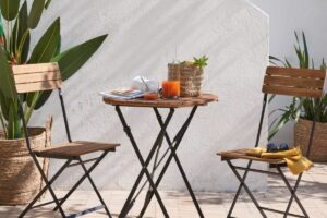 Tavolo CALATHEA Maisons du Monde in acacia su piccolo balcone estivo