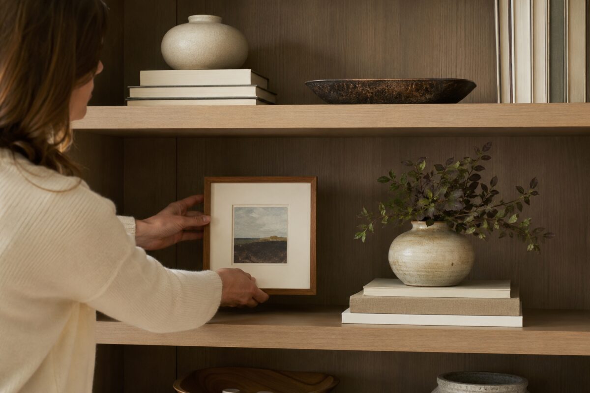 Mensola con libri impilati vaso in ceramica quadro e spazi vuoti equilibrati