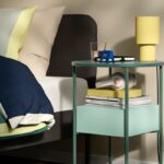 Comodino IKEA BLANKHÄLLAN verde e turchese accanto a un letto alto