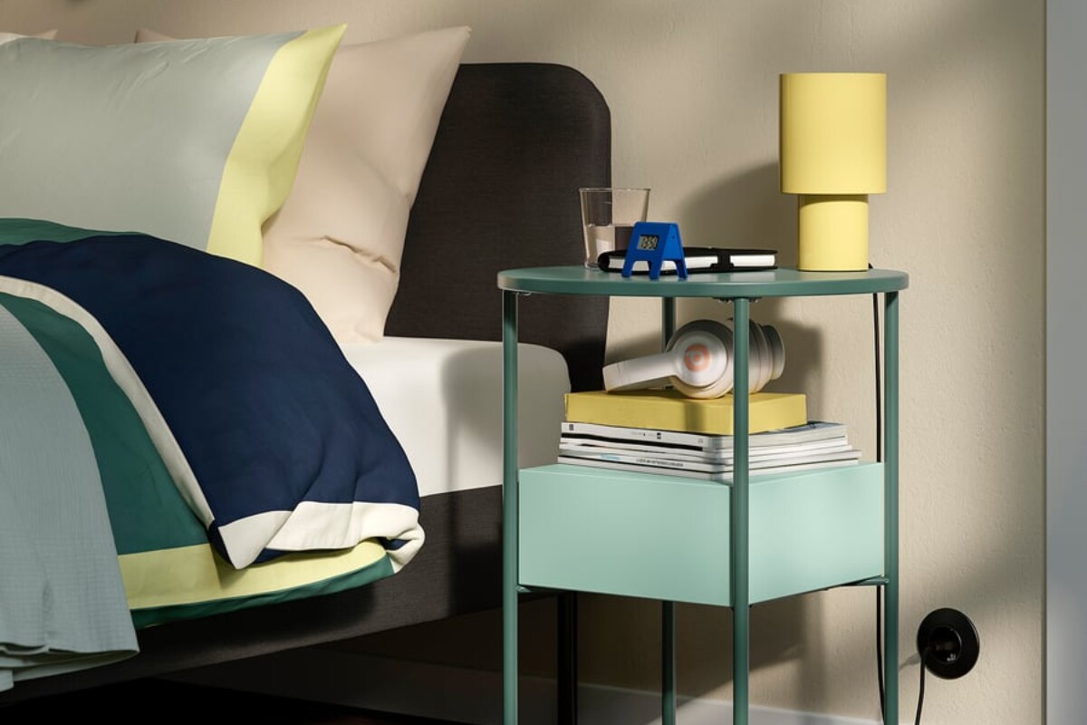 Comodino IKEA BLANKHÄLLAN verde e turchese accanto a un letto alto