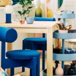 Sedie blu IKEA PS 2026 attorno a un tavolo in una cucina luminosa