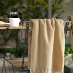 Plaid IKEA HOLMVI beige giallo con frange su una sedia in legno in un ambiente accogliente
