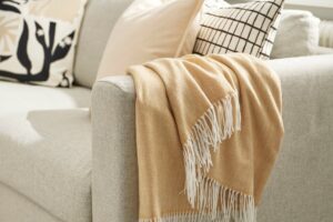 IKEA scalda il divano con un plaid beige giallo che illumina i neutri autunnali