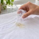 Detergente liquido applicato su una macchia di crema solare sul colletto