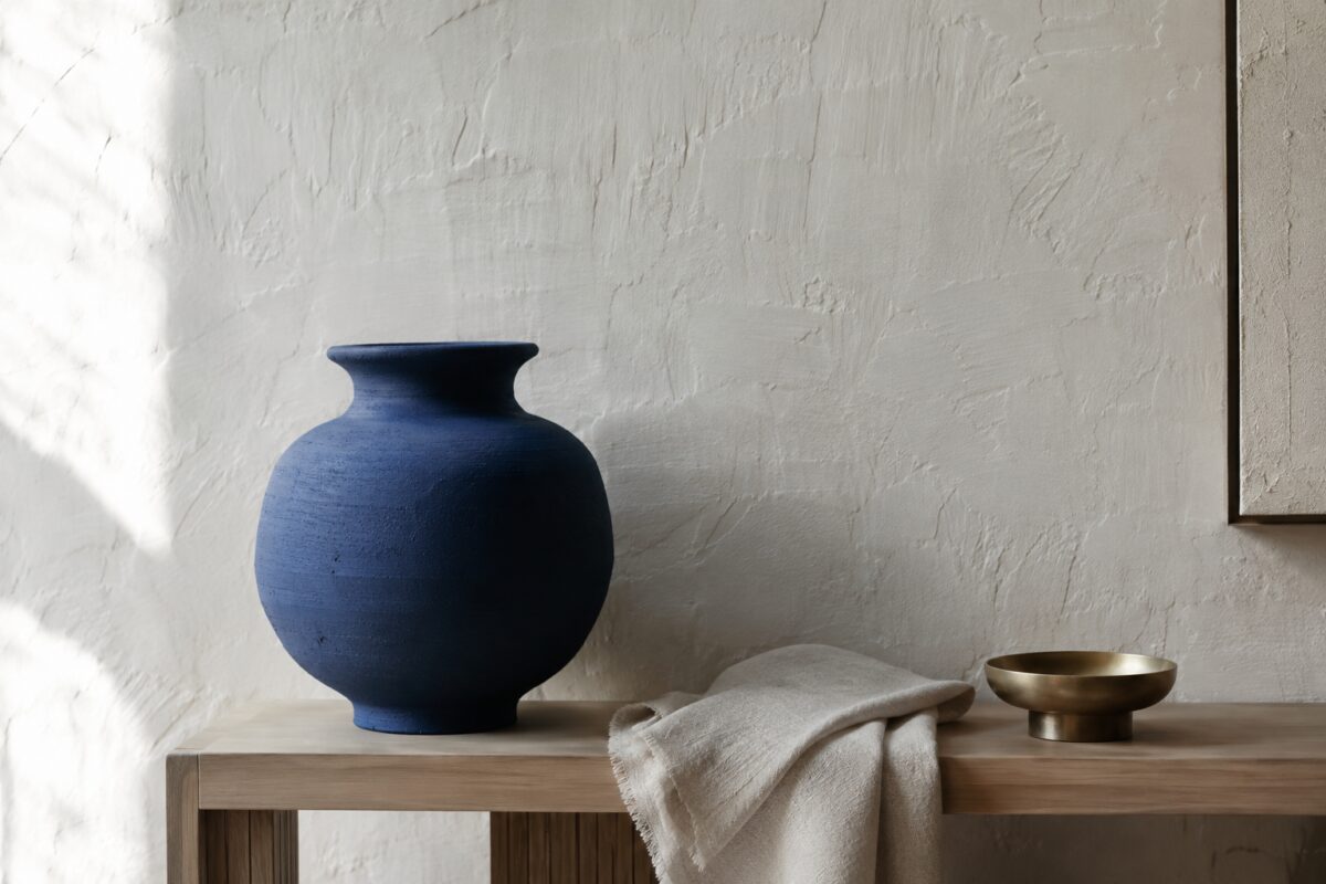 Dettaglio di ceramica blu, lino naturale e intonaco bianco calce