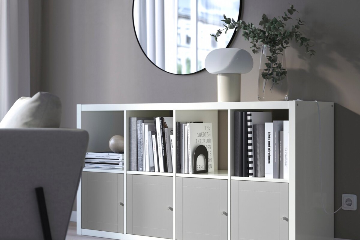 Scaffale KALLAX bianco arredato con libri e vani chiusi in un soggiorno luminoso
