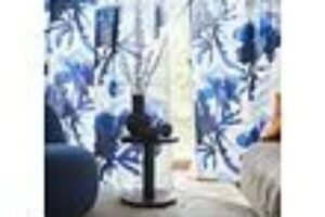 Le tende floreali a tutta altezza filtrano la luce e slanciano la stanza