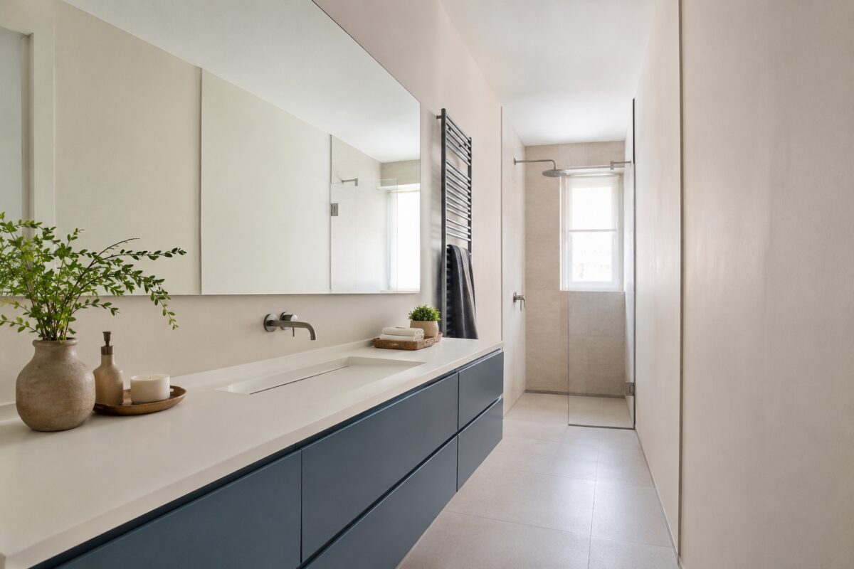 Grande specchio continuo che riflette luce naturale in un bagno stretto