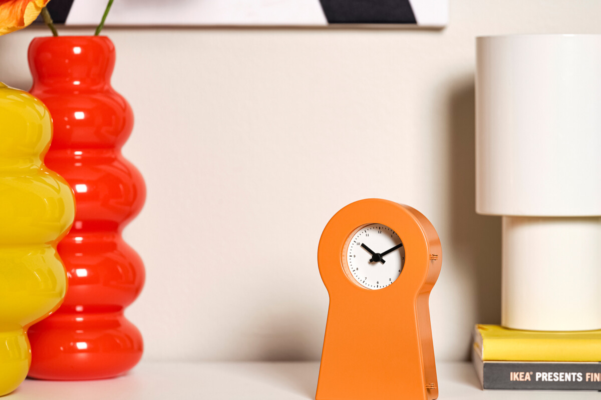 Orologio arancione IKEA PS 1995 su una mensola con libri e decorazioni
