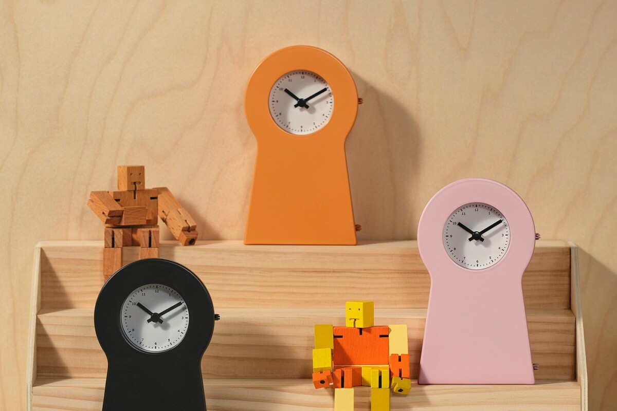 Tre orologi IKEA PS 1995 in arancione rosa e nero esposti su una mensola