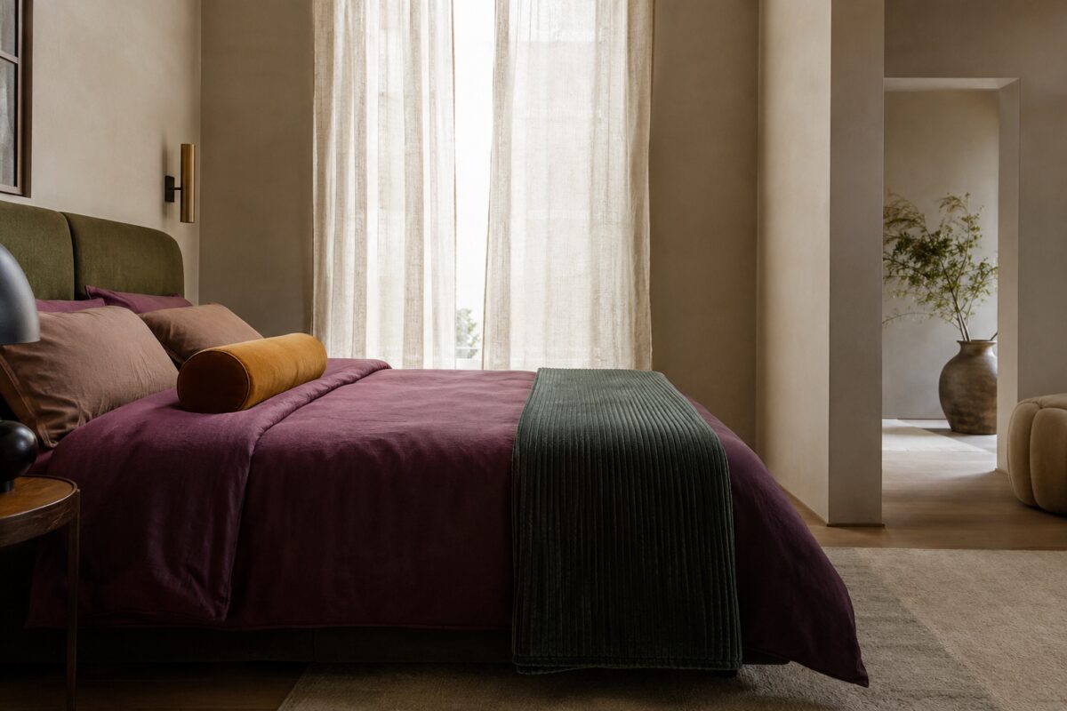 Letto con plaid piegato sul terzo inferiore e cuscini coordinati