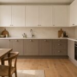 Cucina bianca con basi color taupe argilloso, piano chiaro e pavimento in rovere