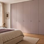 Camera con armadio a tutta altezza dalle ante rosa malva grigiato e letto écru
