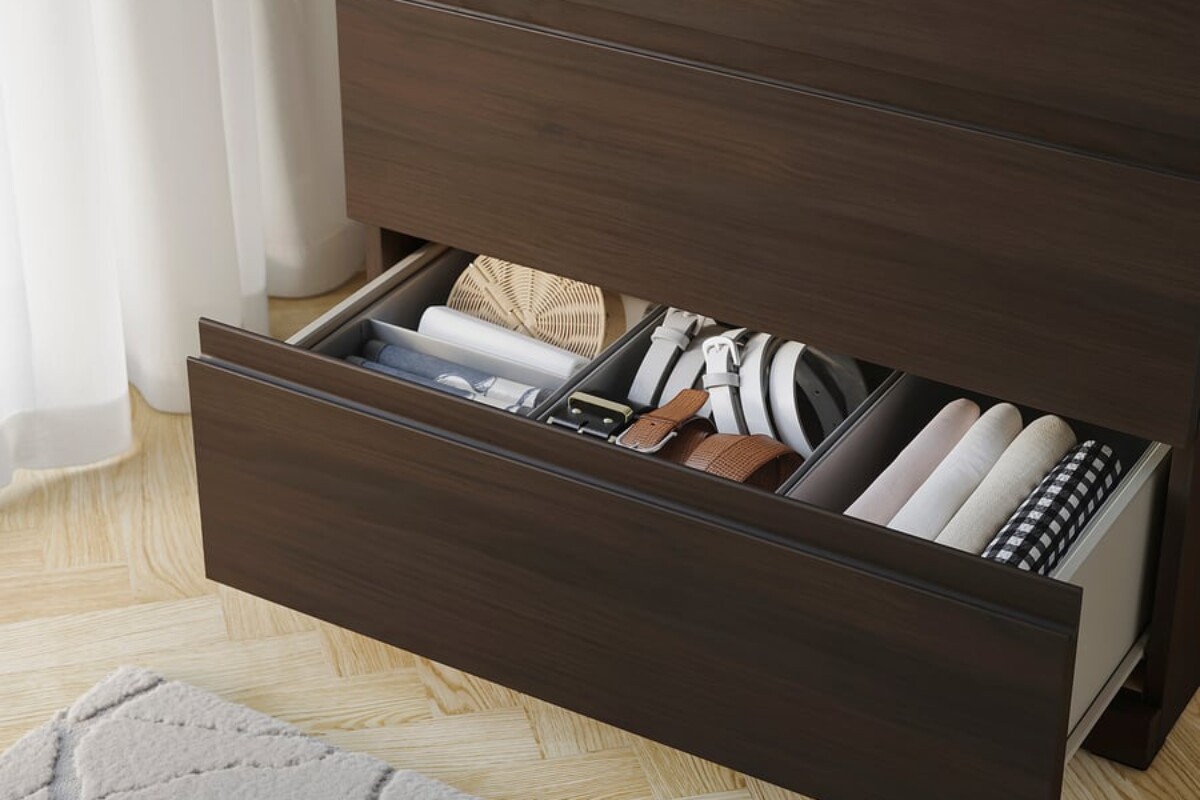 Cassetto aperto della STORKLINTA IKEA con abiti e accessori organizzati